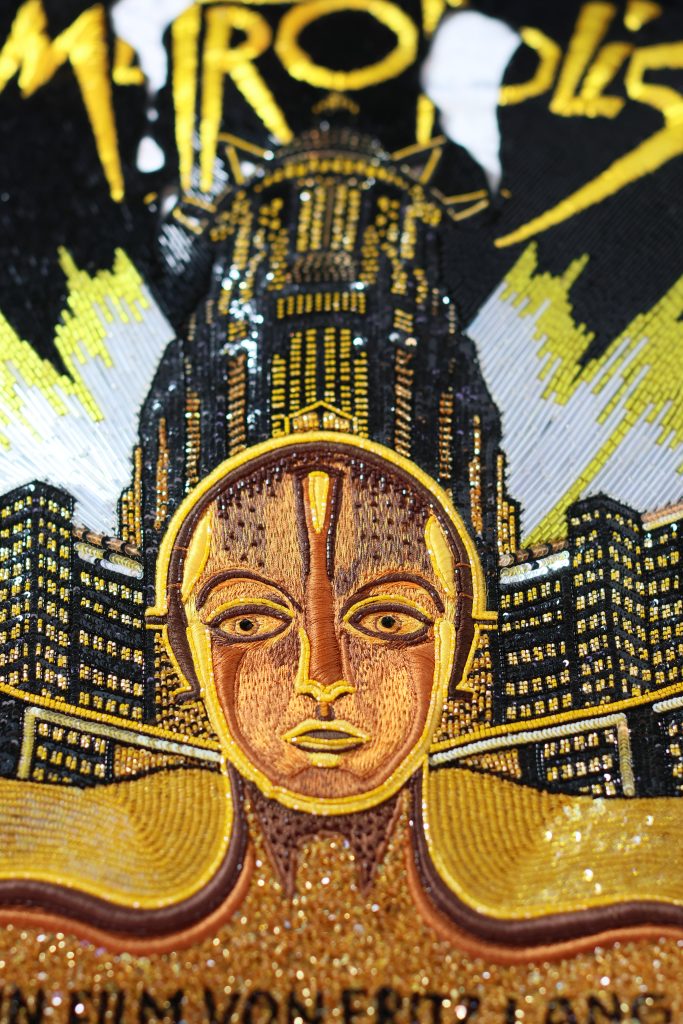 Metropolis poster hand-embroidered by Ricamour. Thread work, beaded textures, bespoke art for luxury spaces.
