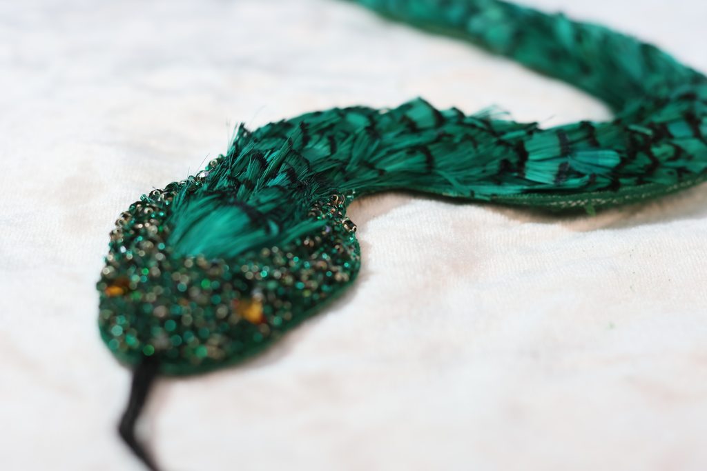 Hand embroidered snake crafted with crystals and feathers by Ricamour